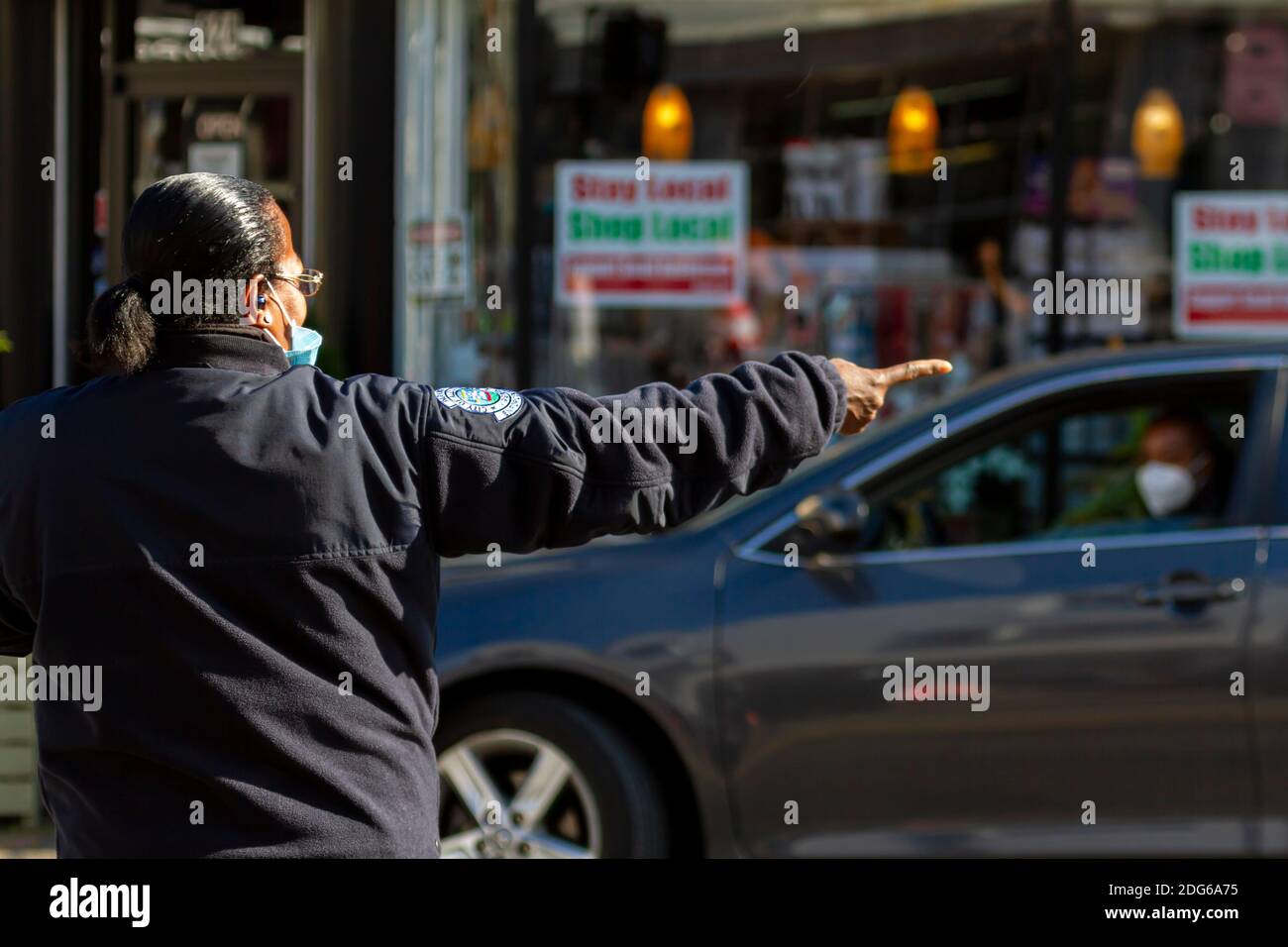 Alexandrie, va, USA 11-28-2020: Une femme africaine américaine policier portant un masque facial en raison de COVID-19 montre la direction à un conducteur qui ha Banque D'Images