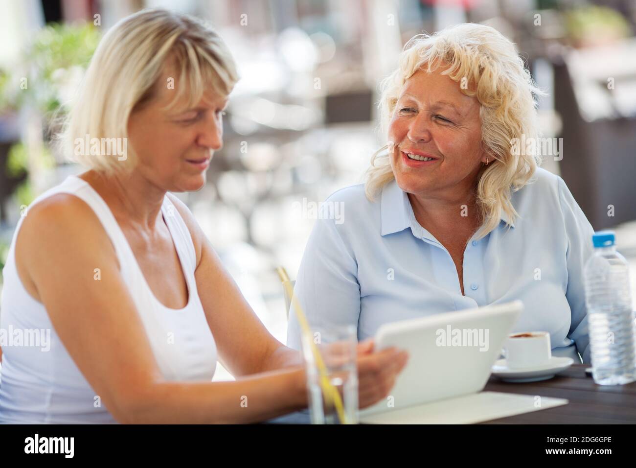 Les femmes âgées passent du temps avec PAD dans un café en plein air Banque D'Images
