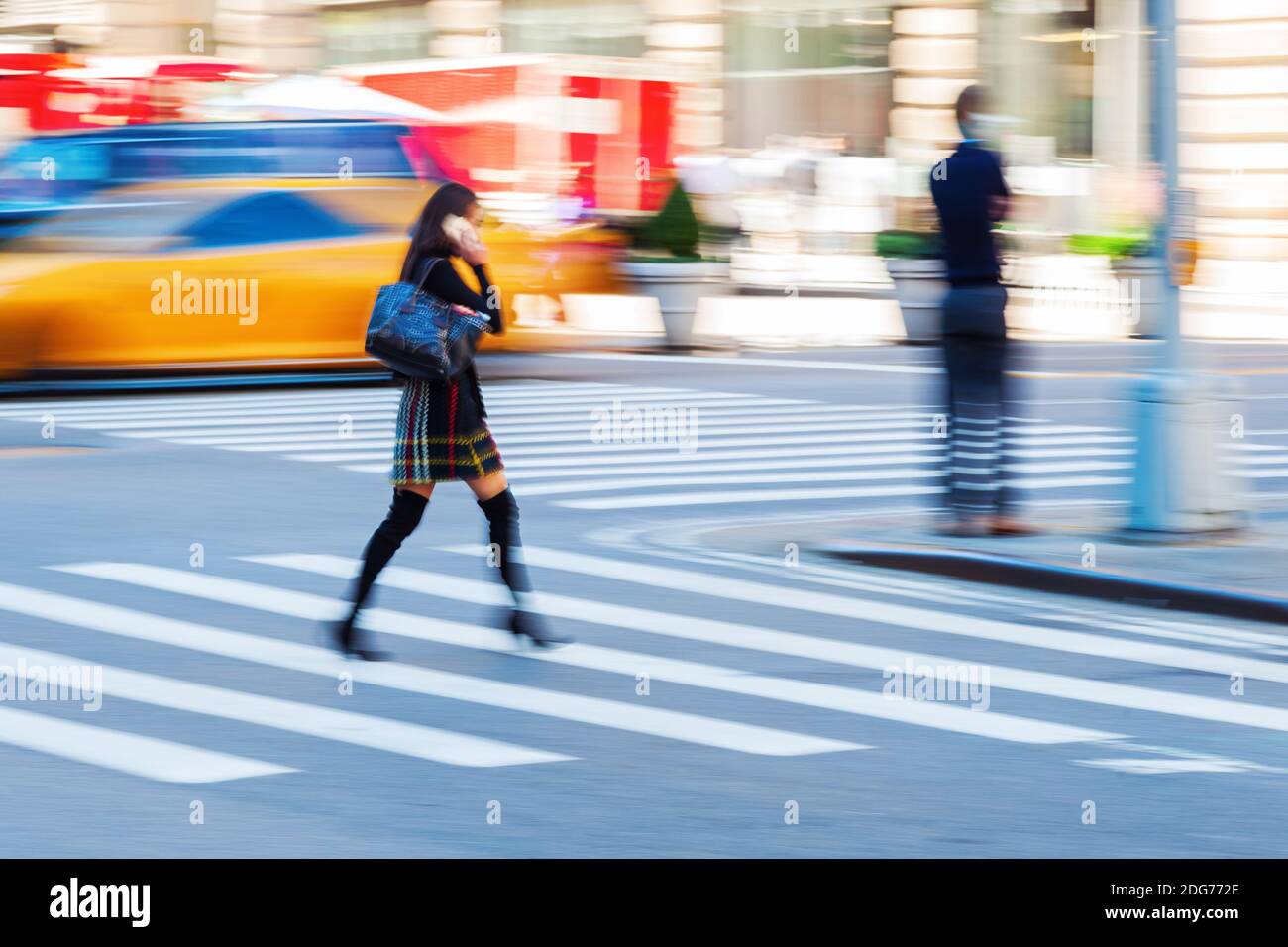 Image en mouvement flou d'une femme traversant une rue pendant qu'elle téléphone Banque D'Images Image en mouvement flou d'une femme traversant une rue pendant qu'elle téléphone Banque D'Images