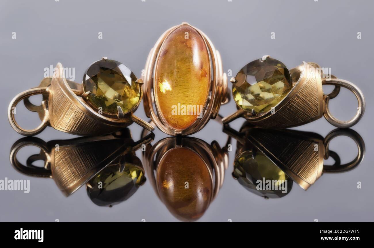 Vieux boucles d'oreilles en or avec pierres vertes et une bague avec orange Banque D'Images