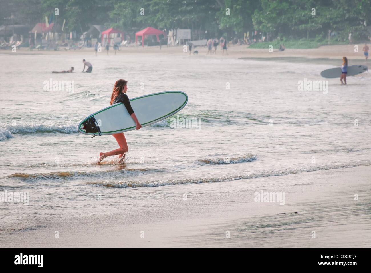 Une femme avec une planche de surf sort de l'eau. Spot de surf avec vagues de mousse pour débutants. Sri Lanka, Weligama Banque D'Images