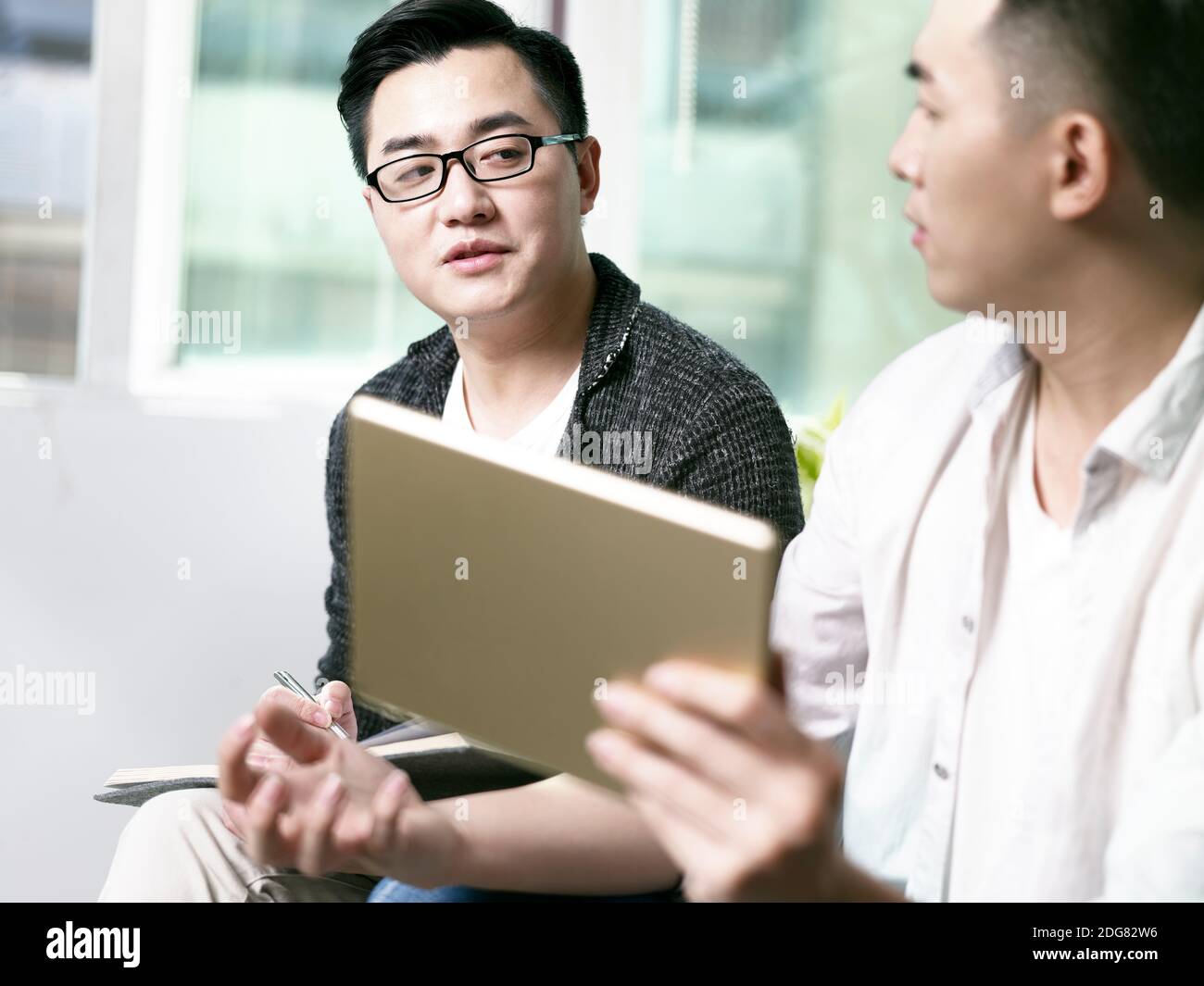 deux jeunes entrepreneurs asiatiques discutant des affaires au bureau en utilisant le numérique tablette Banque D'Images