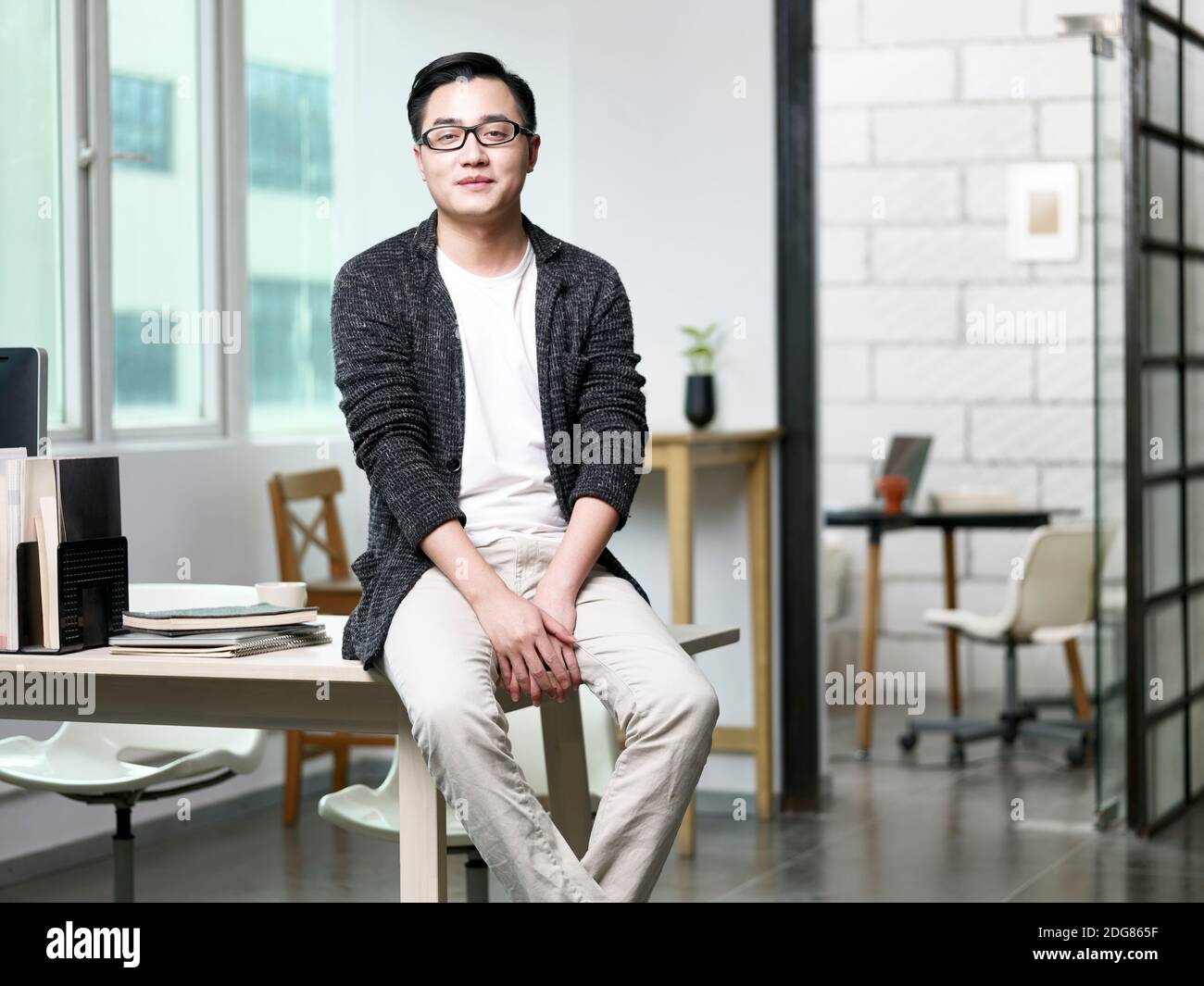 portrait d'un jeune homme d'affaires asiatique assis au bureau regarder l'appareil photo sourire Banque D'Images