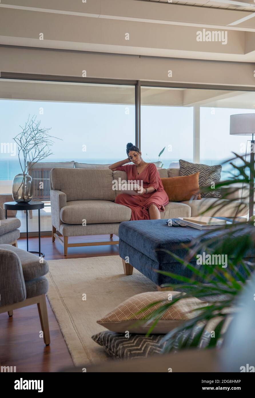 Femme se détendant avec une tablette numérique sur un canapé dans un salon de luxe chambre Banque D'Images