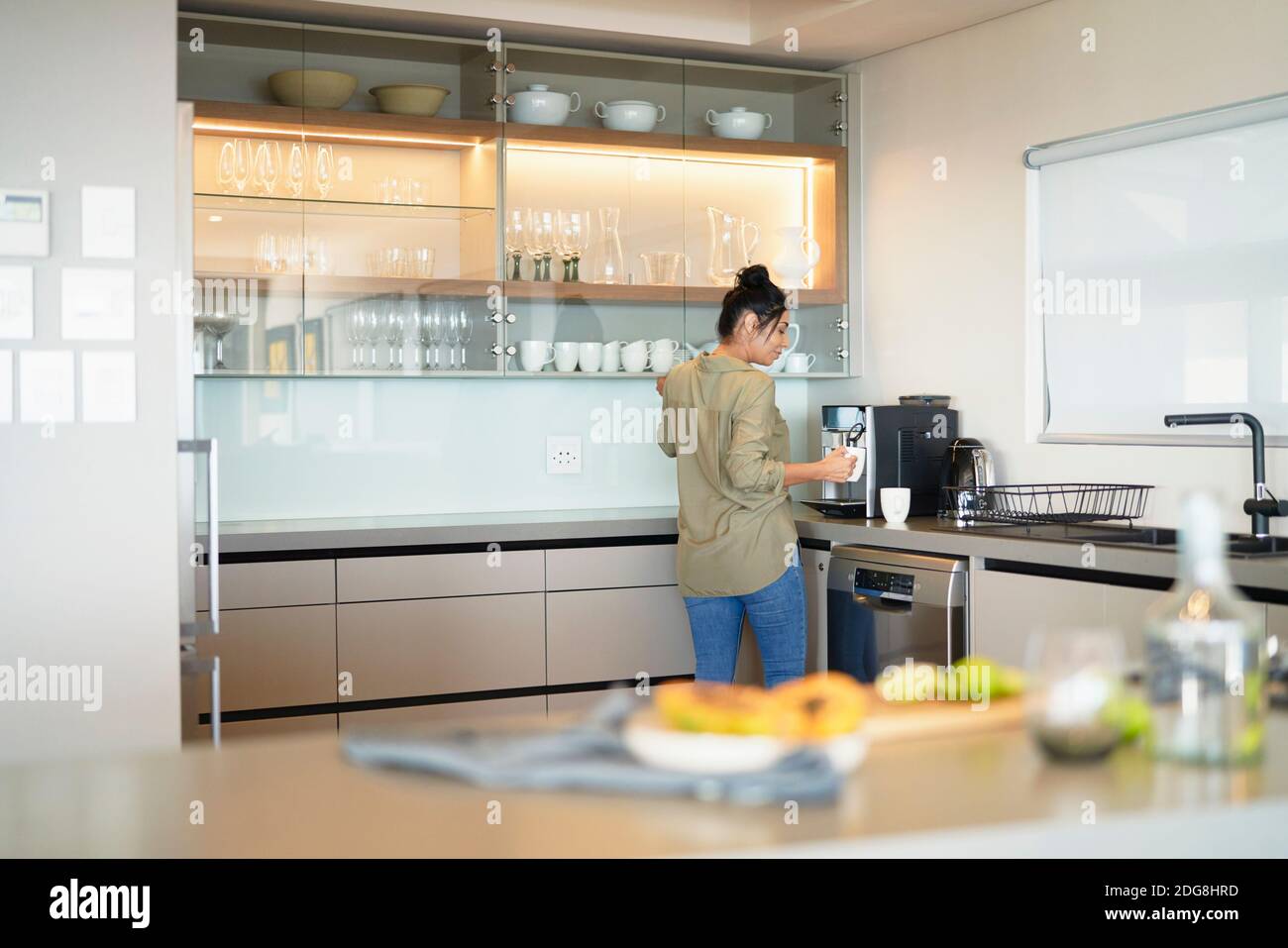 Femme préparant un espresso à la machine dans la cuisine moderne de la maison Banque D'Images