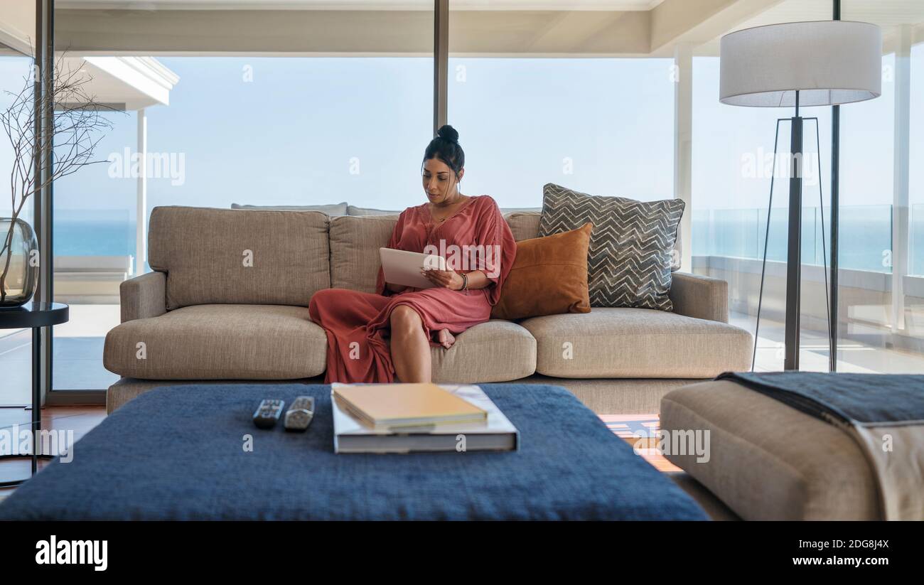 Femme se détendant avec une tablette numérique sur un canapé-vitrine de luxe Banque D'Images