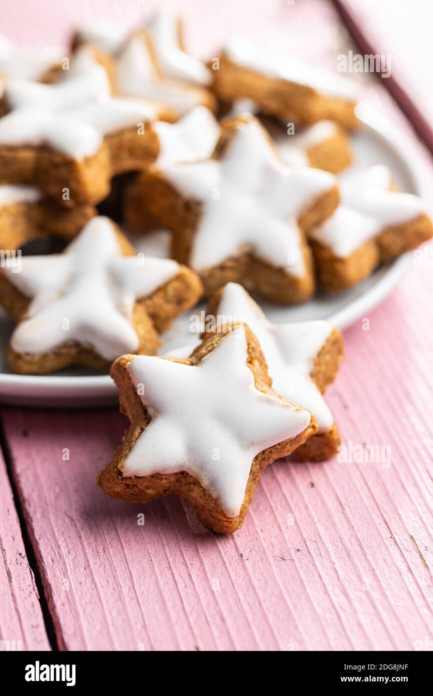 Le glaçage des étoiles de pain d'épice. Biscuits de Noël traditionnels sur une table en bois rose. Banque D'Images