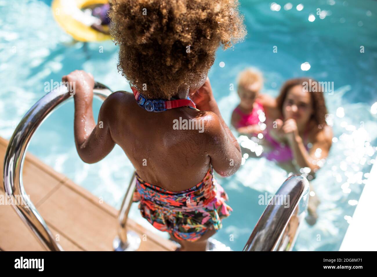 La mère qui regarde sa fille se baigner dans la piscine d'été ensoleillée Banque D'Images
