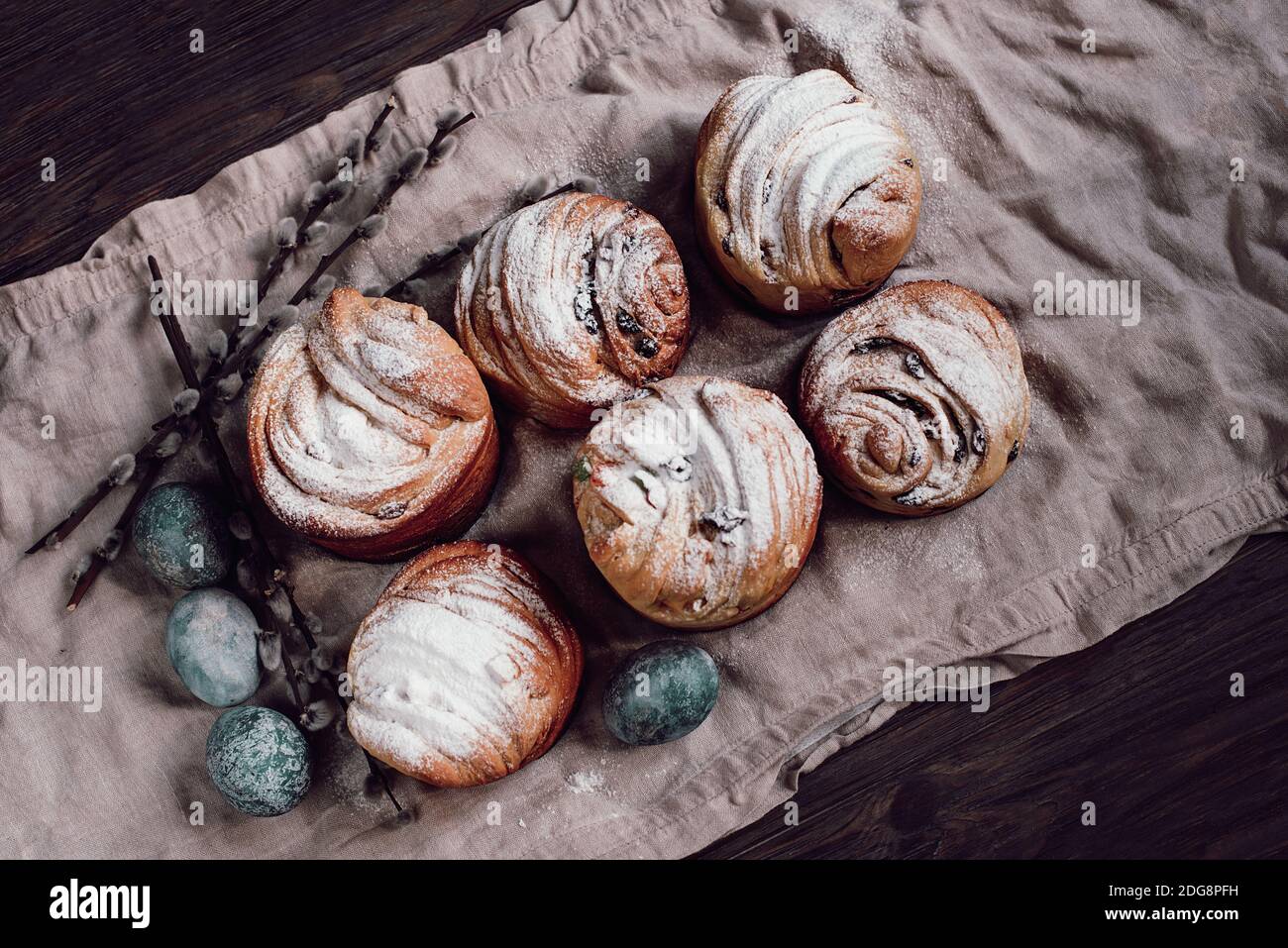 Gâteau traditionnel gâteau de Pâques kraffin aux raisins secs sur fond de bois foncé. Gâteau maison Cruffin aux fruits confits. Œufs naturellement peints avec Banque D'Images