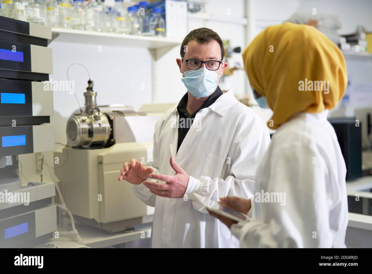 Scientifiques dans les masques de visage parlant en laboratoire Banque D'Images