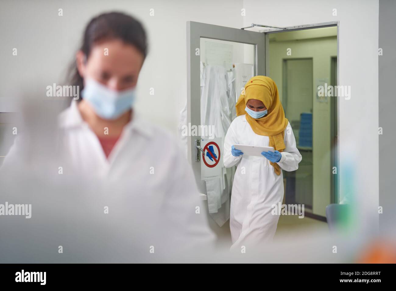 Femme scientifique dans le masque facial et hijab utilisant la tablette numérique Banque D'Images