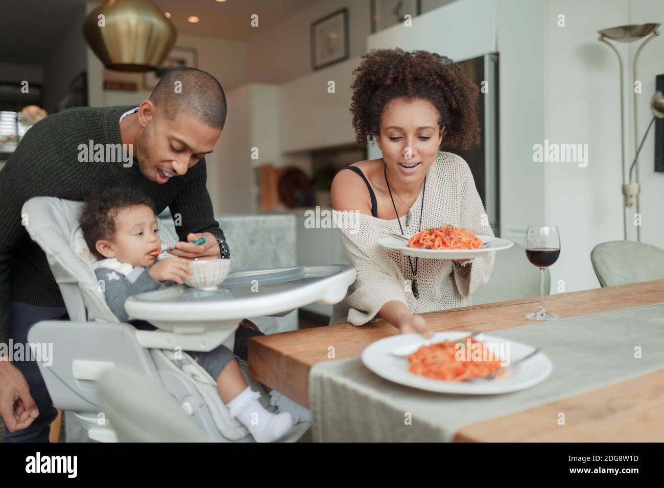 Couple mangeant des spaghetti et nourrissant bébé fille à la table de salle à manger Banque D'Images