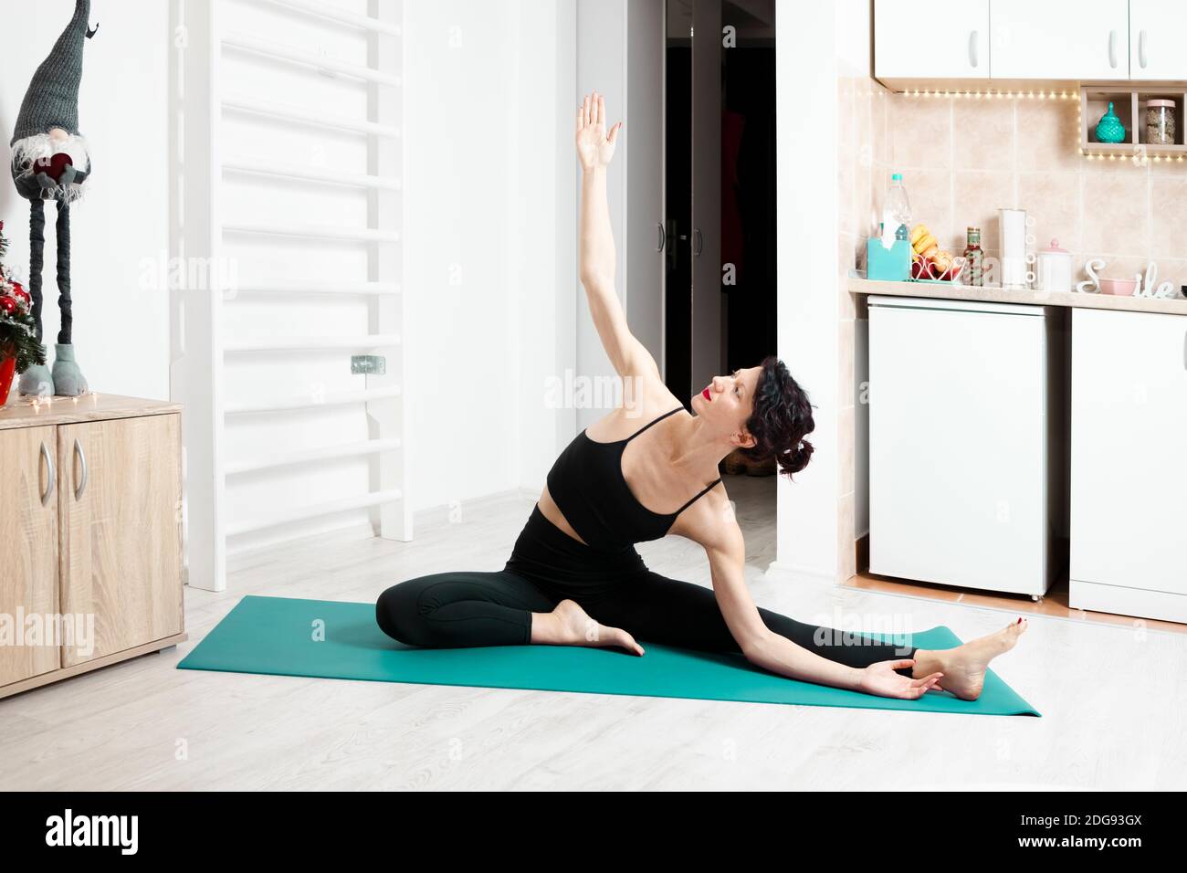 Jeune femme pratiquant le yoga dans son propre appartement et appréciant son jour Banque D'Images