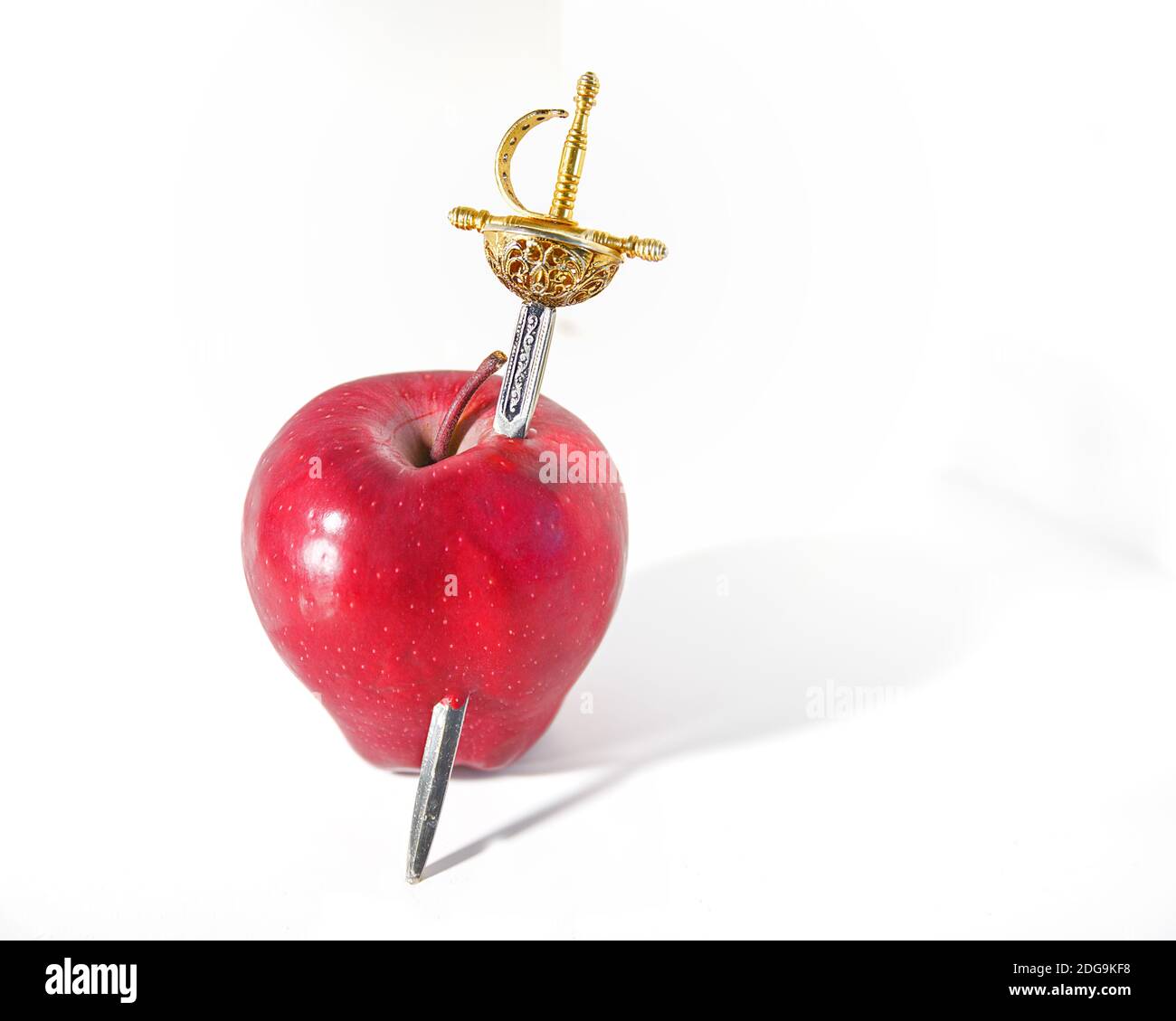 Ouvre-lettre épée. Copiez l'ouvre-épée en papier antique SpaceGold dans une pomme rouge vif. Arrière-plan blanc. Espace pour écrire. Image de stock. Banque D'Images