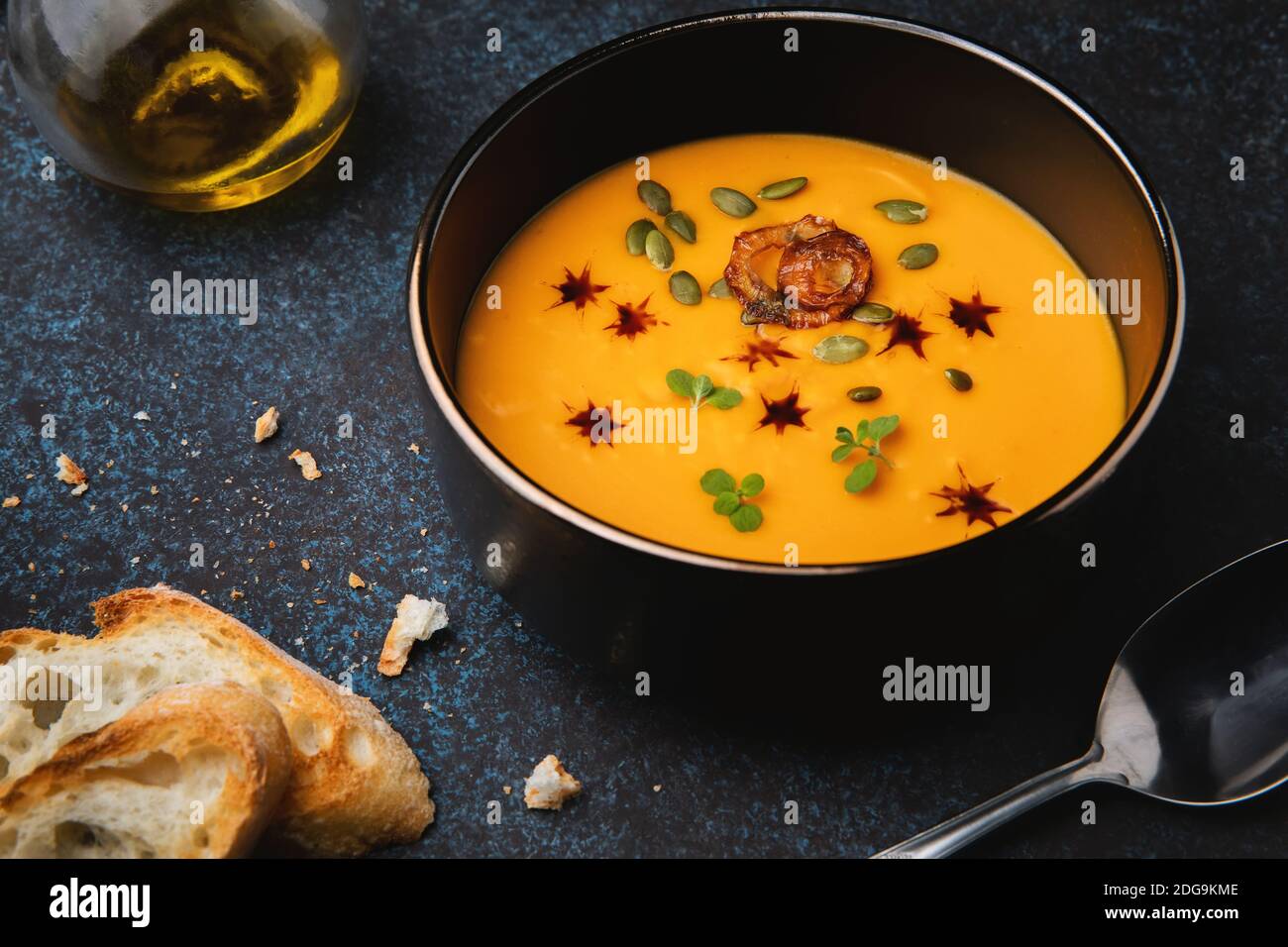 Soupe à la crème de potiron à l'oignon, aux herbes, aux graines de potiron, à l'huile de potiron et à la baguette grillée. Plats végétariens. Banque D'Images