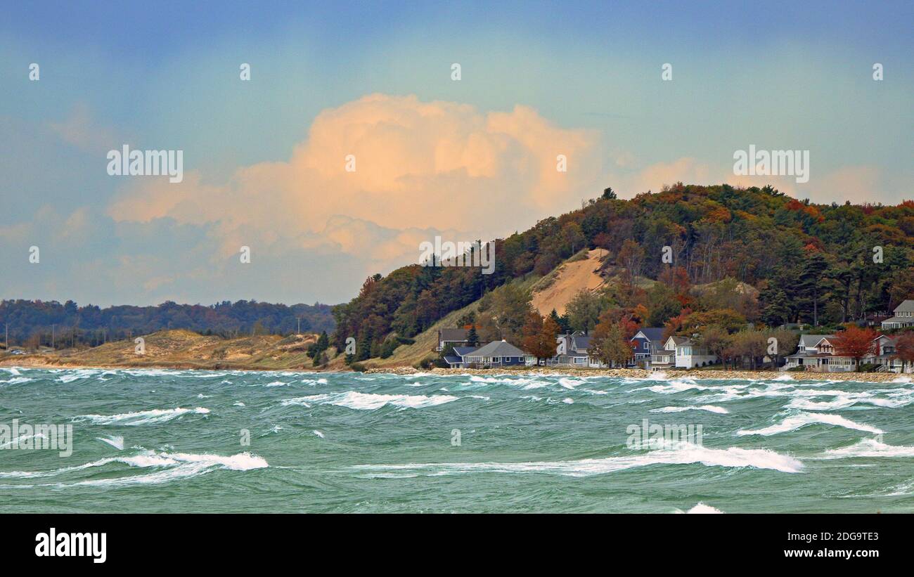 Rive du lac Michigan avec chalets et arbres dans le feuillage d'automne par une journée venteuse avec de grandes vagues Banque D'Images