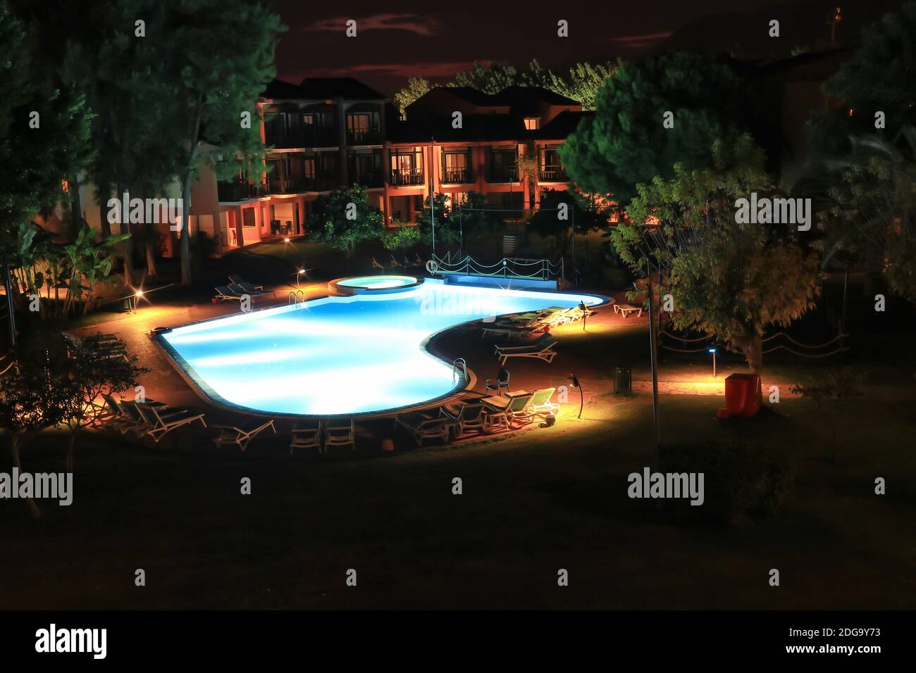 Vue de la fenêtre en soirée sur la cour de l'hôtel avec piscine Banque D'Images