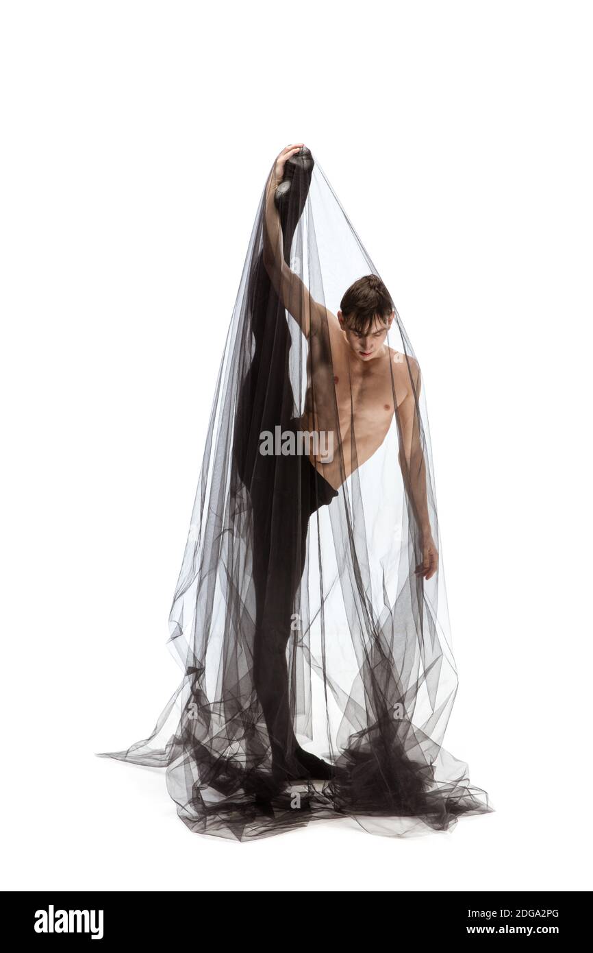 Fort. Danseuse de ballet classique élégante isolée sur fond de studio blanc. Homme en tissu noir minimaliste a l'air gracieux, inspiré. La grâce, l'artiste, le mouvement, l'action et le concept de mouvement. Banque D'Images