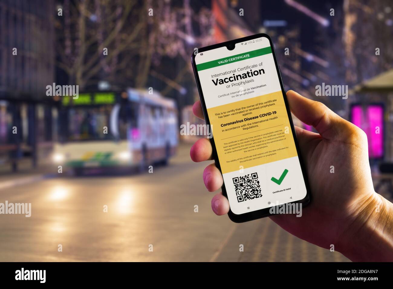 Smartphone affichant un certificat de vaccination numérique valide pour le COVID-19 dans la main d'homme, le centre-ville et le bus de ville en arrière-plan. Vaccination, maladie i Banque D'Images
