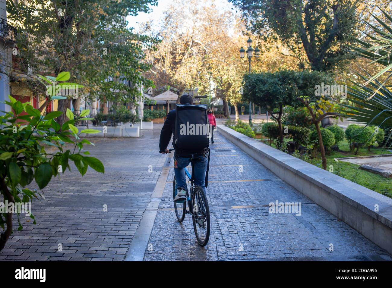 Centre ville d'Athènes, Grèce. Décembre 5 2020. Biker avec un sac à dos sur une rue pavée vide, jour d'hiver. COVID 19 confinement en cas de pandémie Banque D'Images