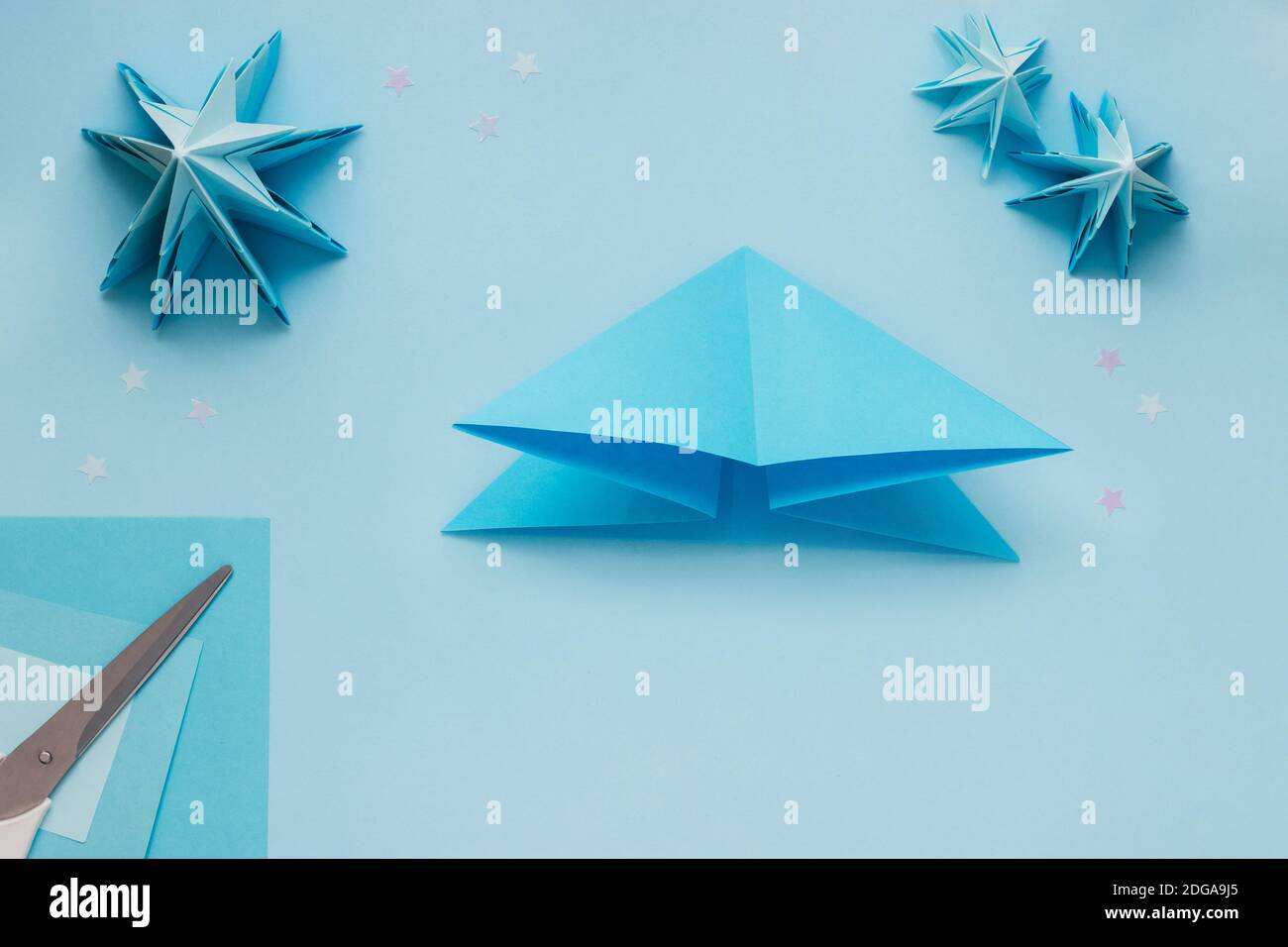 Arbre de Noël en relief origami simple en papier bleu. Instructions étape par étape, étape 7. Tirez les plis horizontaux l'un vers l'autre et pliez-les pour former un triangle Banque D'Images