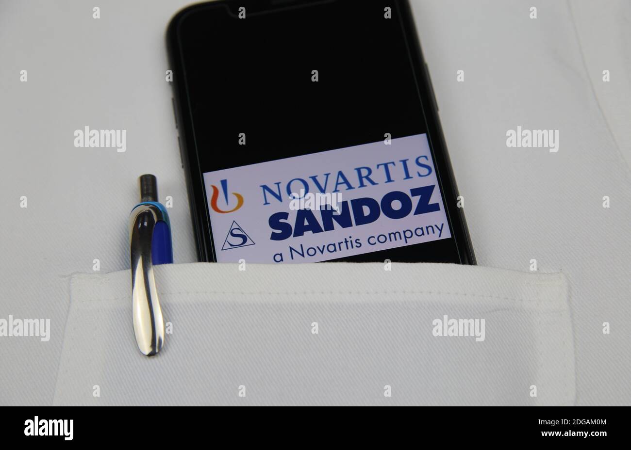 Viersen, Allemagne - avril 9. 2020: Gros plan de l'écran de téléphone mobile avec le logo de la société pharmaceutique Novartis Sandoz dans la poche d'un document blanc Banque D'Images