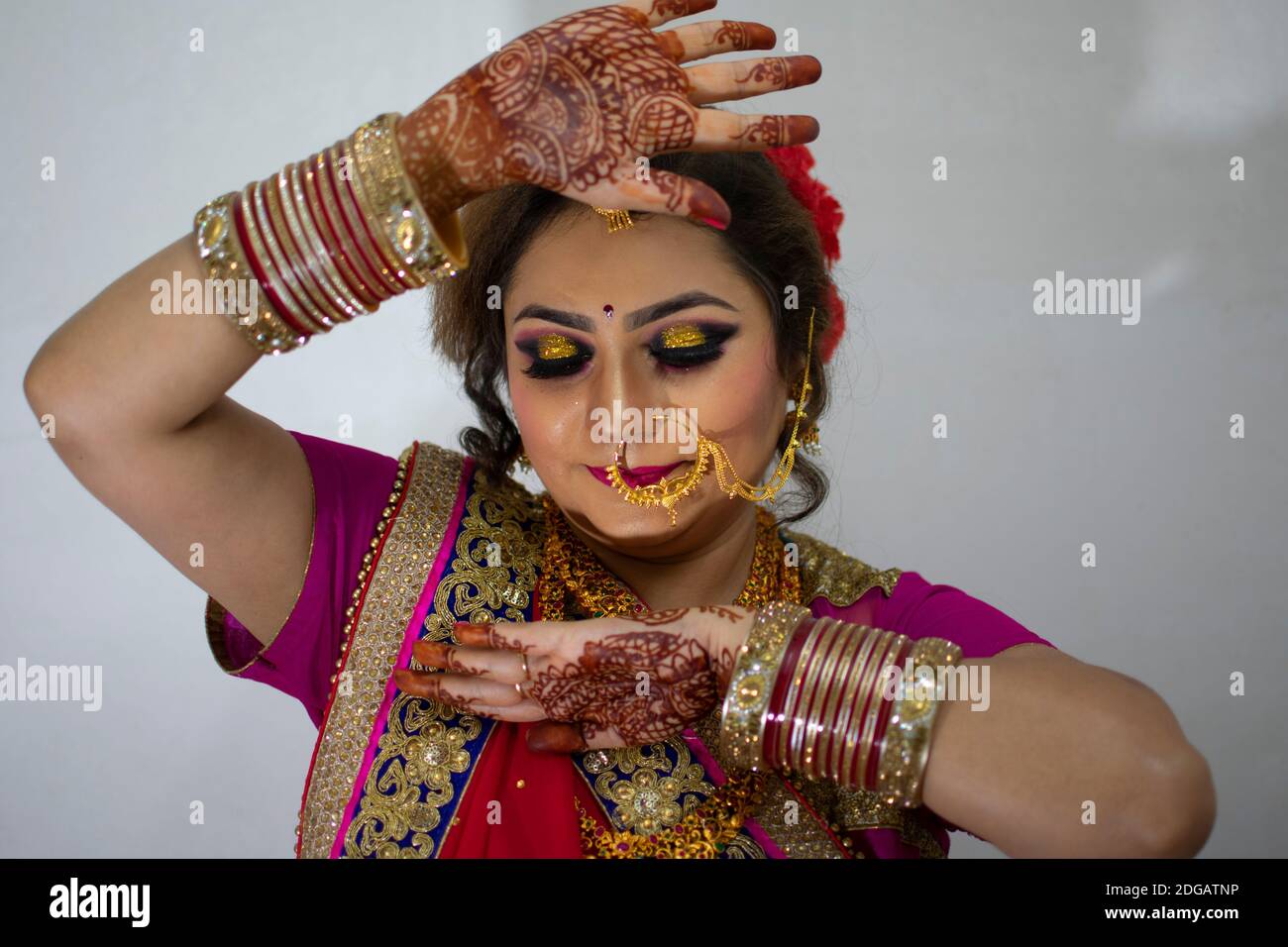 une belle fille indienne en robe de mariée portant une saree rouge et des ornements dorés montrant le tatouage appelé mehindi Banque D'Images