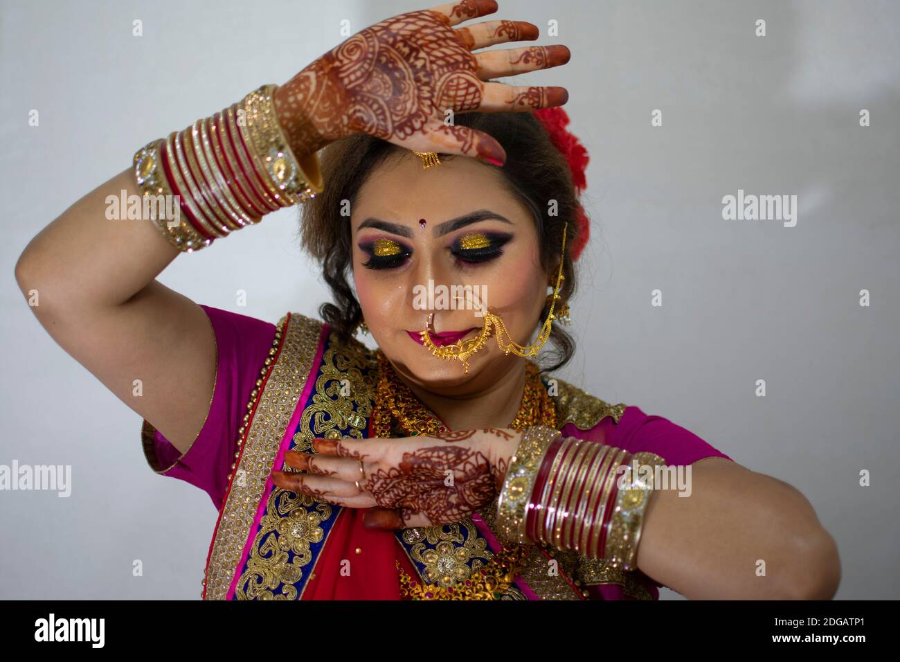 une belle fille indienne en robe de mariée portant une saree rouge et des ornements dorés montrant le tatouage appelé mehindi Banque D'Images