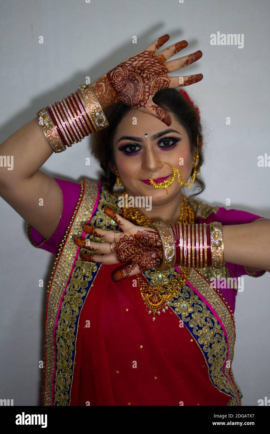 une belle fille indienne en robe de mariée portant une saree rouge et des ornements dorés montrant le tatouage appelé mehindi Banque D'Images