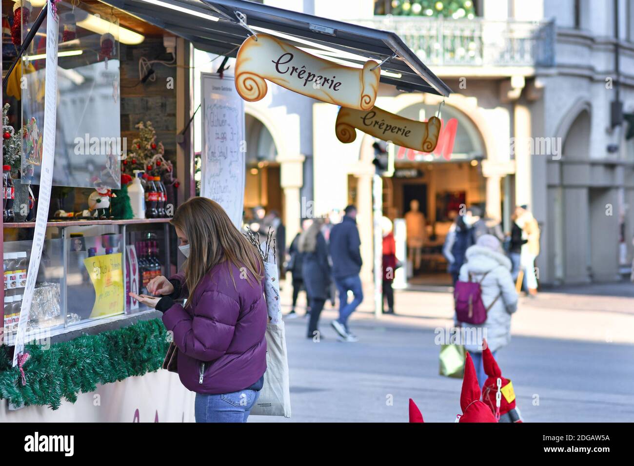 Heidelberg, Allemagne - décembre 2020: Femme avec masque de visage achetant de la nourriture au stand de crepe de Noël pendant la pandémie de Corona Banque D'Images