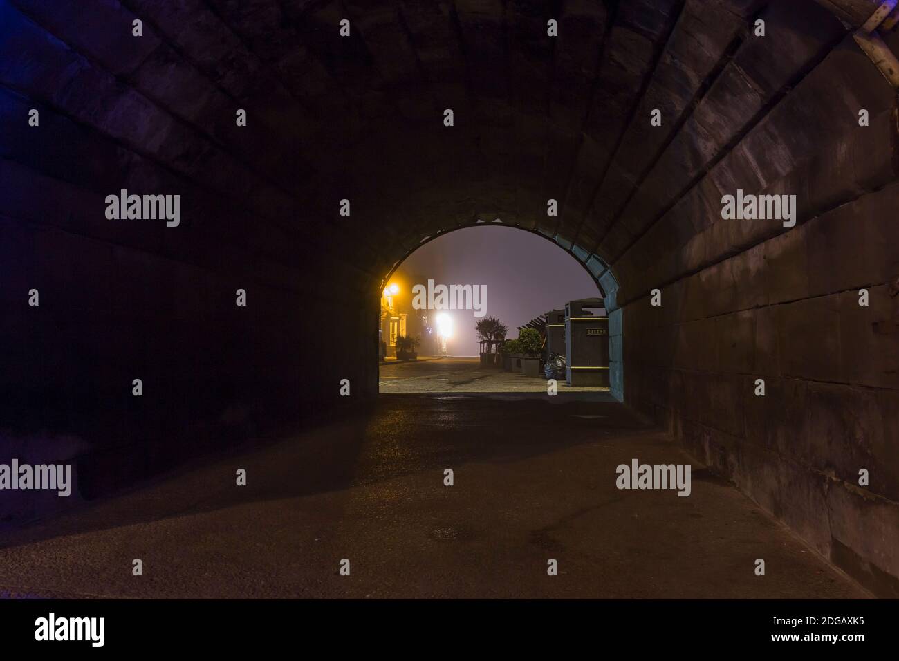 Ambiance, scène de rue en soirée en regardant à travers un vieux tunnel de briques la nuit. Vue de l'éclairage de rue à travers le tunnel en pierre sombre. Banque D'Images