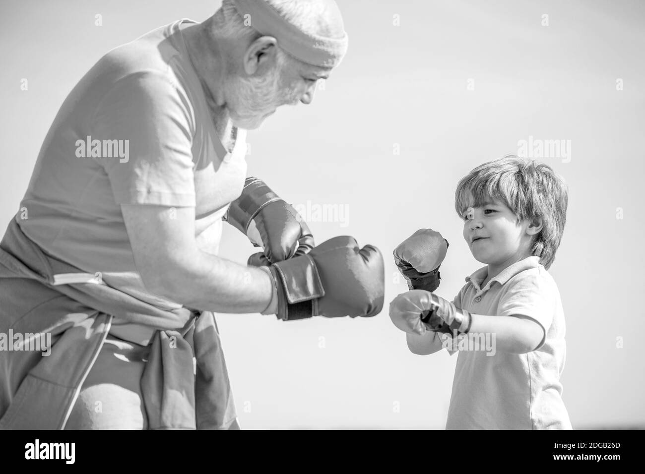 Le père forme sa boxe de fils. Petit sportif de garçon à l'entraînement de boxe avec entraîneur. Noir et blanc Banque D'Images