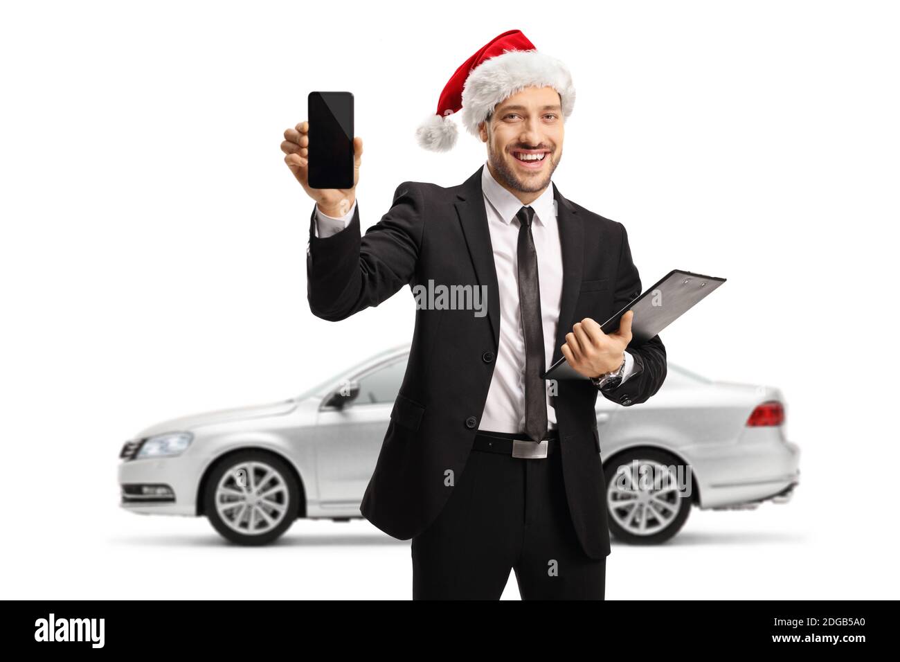 Homme d'affaires avec un téléphone portable portant un chapeau du père noël et en posant devant une voiture argentée isolée sur arrière-plan blanc Banque D'Images