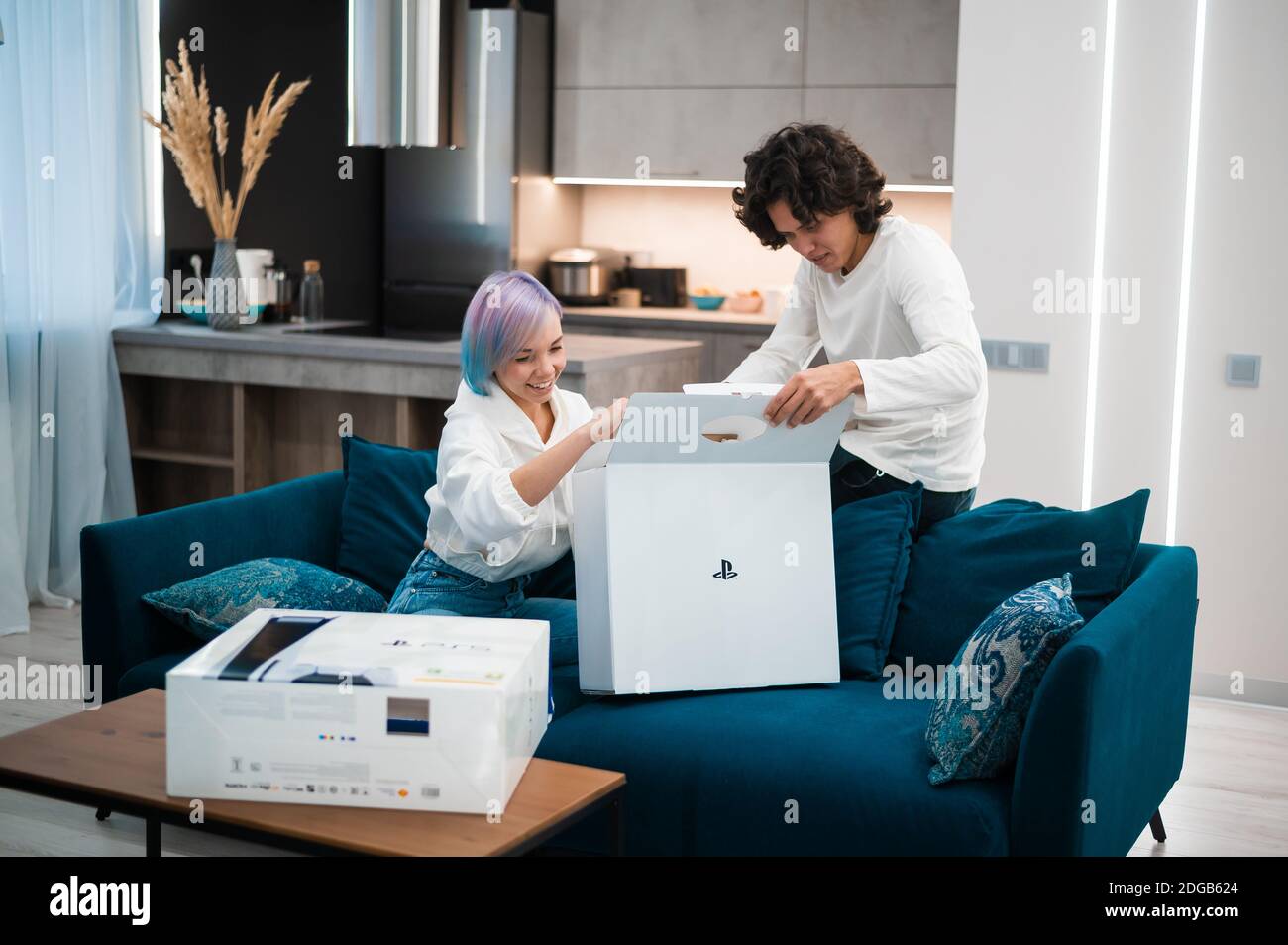 Un jeune couple heureux qui débarque la toute nouvelle console de jeu Sony PlayStation 5 chez lui. Moscou - novembre 28 2020. Banque D'Images