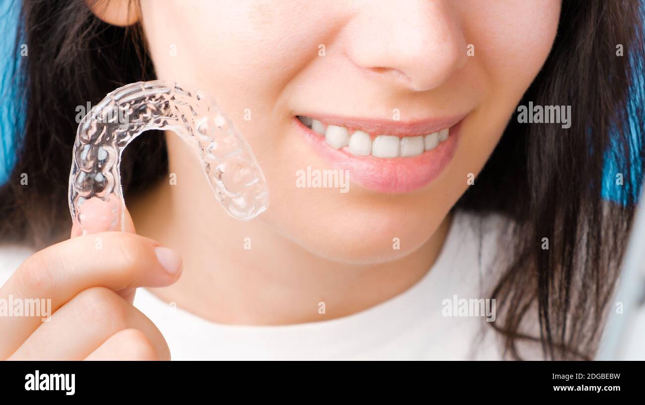 Femme en gros plan tenant une bretelles amovibles transparentes pour un sourire parfait. Aligneurs orthodontiques pour lisser et blanchir les dents. Banque D'Images