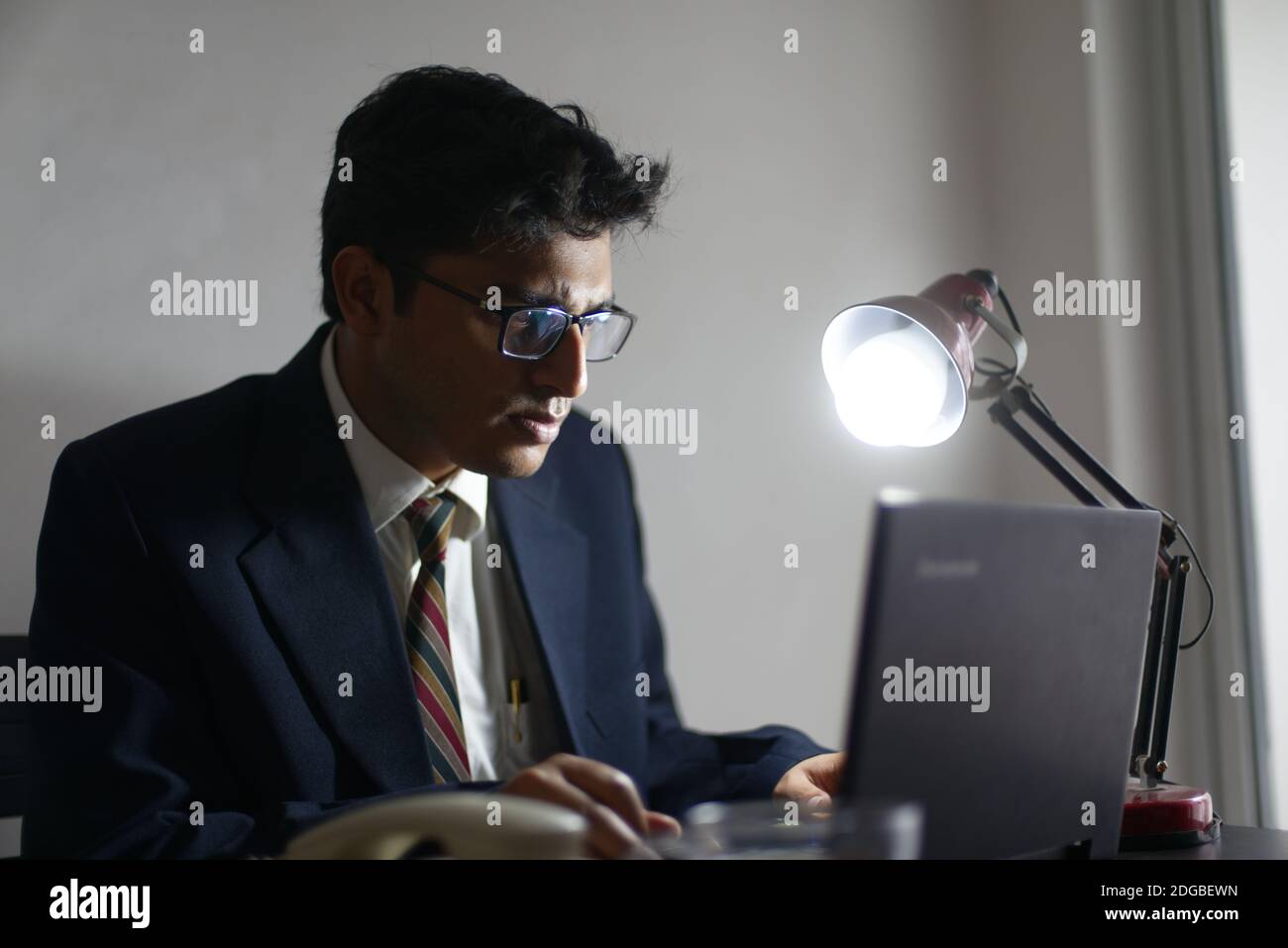 Un bengali indien haut, sombre, beau brune jeune homme/télécabine en tenue de bureau est assis sur une table de bureau dans l'ambiance de travail dans le bureau d'entreprise Banque D'Images