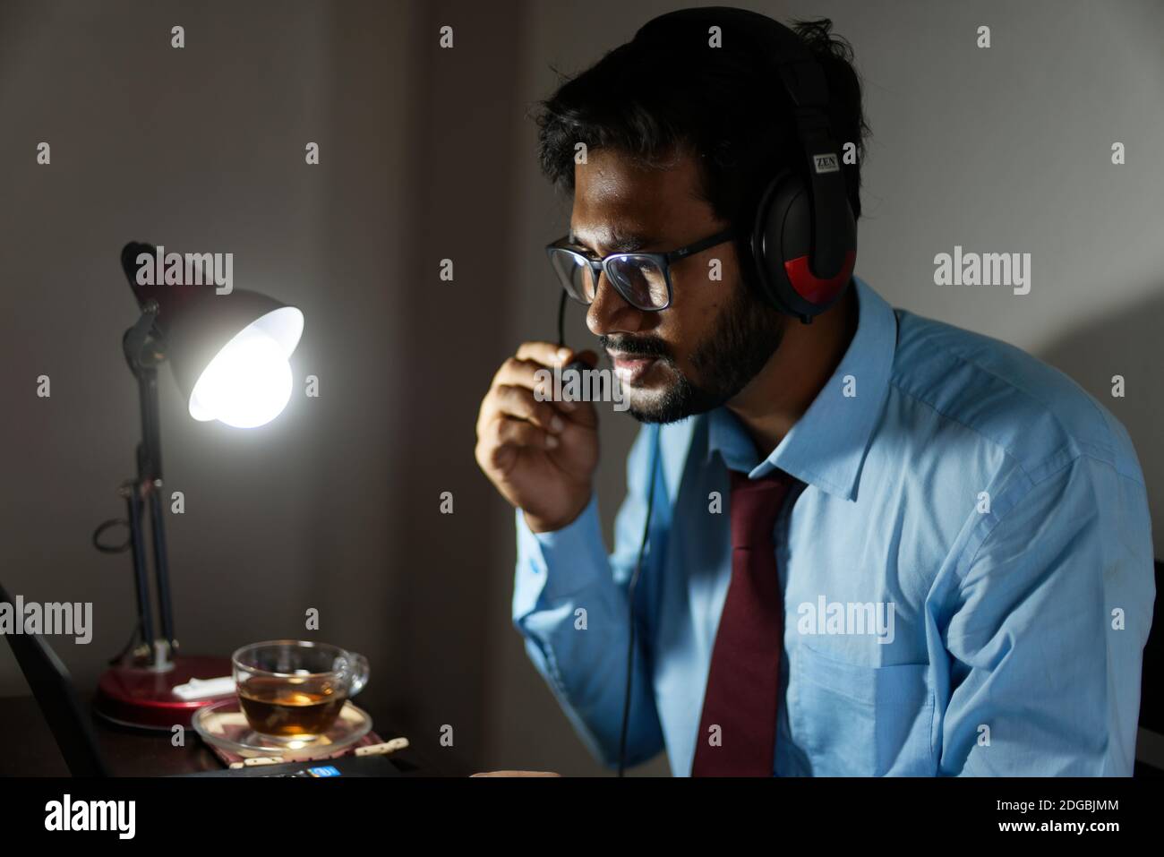 Un bengali indien haut, sombre, beau brune jeune homme/télécabine en tenue de bureau est assis sur une table de bureau dans l'humeur du travail dans un bureau d'entreprise Banque D'Images