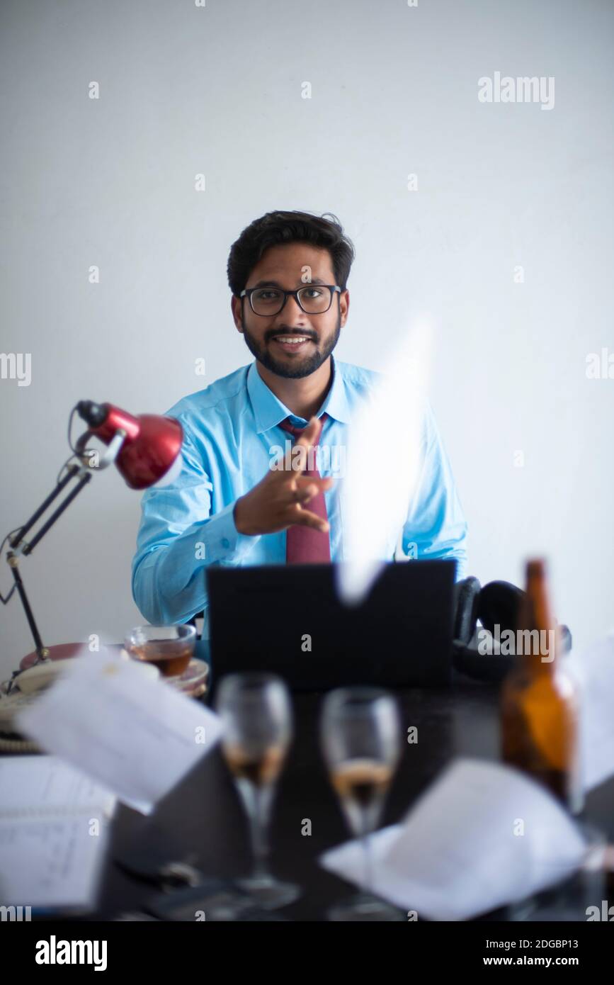 Bengali indien haut, sombre, beau brunes jeune homme en port de bureau appréciant le succès tout en étant assis sur une table de bureau dans un bureau d'entreprise/bpo Banque D'Images