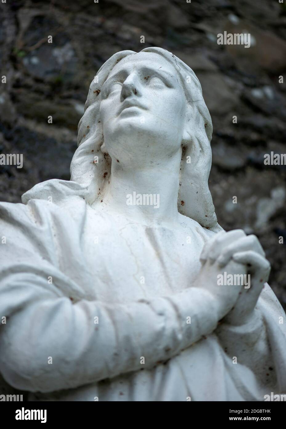 Religion Irlande statue de la figure religieuse blanche a classé les mains contre mise au point sélective du mur de pierre Banque D'Images