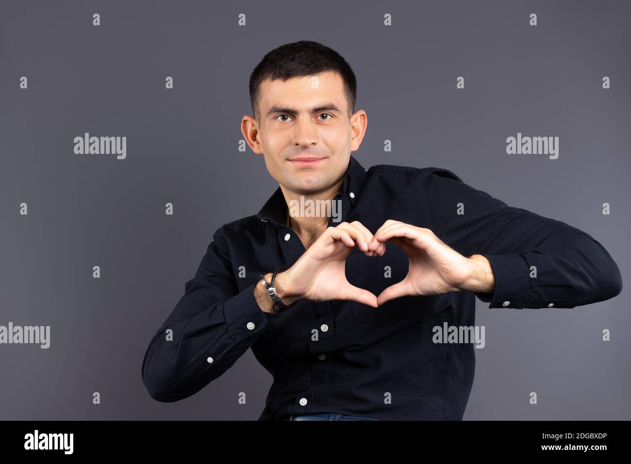 Le don, la charité et le concept de St.Valentin. Homme tenant un cœur hors de ses mains sur un fond noir. Banque D'Images