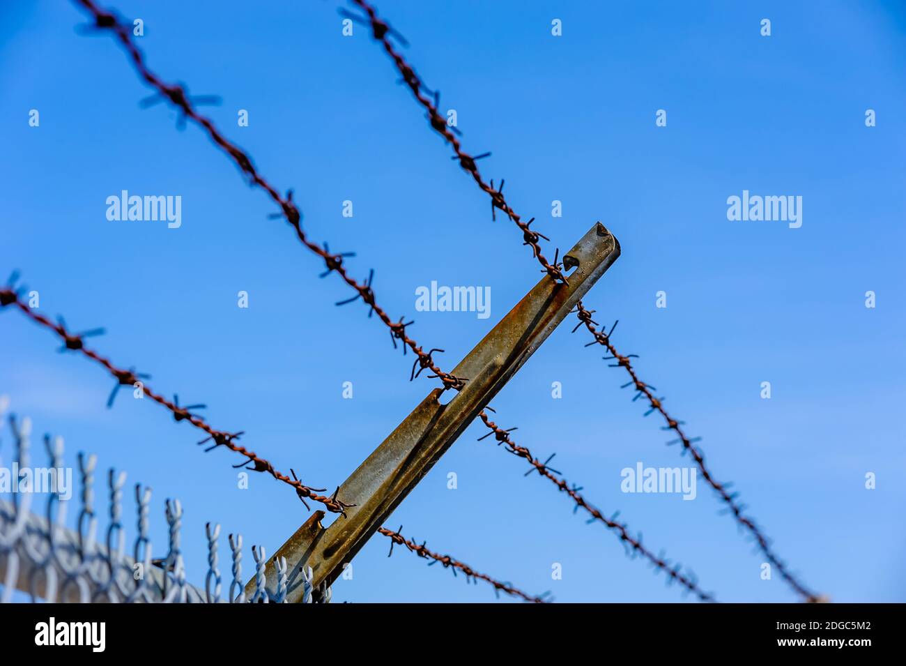 Concentrez-vous sur une partie de la clôture en fil métallique rouillé contre le ciel bleu. Banque D'Images