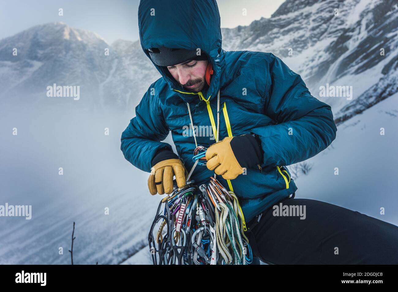 Un homme passe par le rock et l'équipement d'escalade de glace pendant une ascension en hiver Banque D'Images