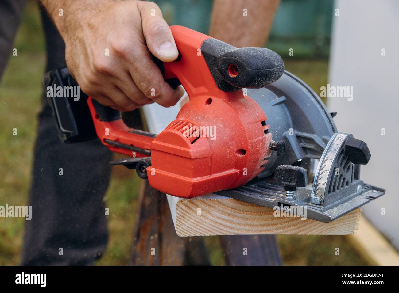 Le travailleur de l'entrepreneur en bâtiment utilise une scie circulaire manuelle pour couper les planches sur un nouveau projet de construction de maison Banque D'Images