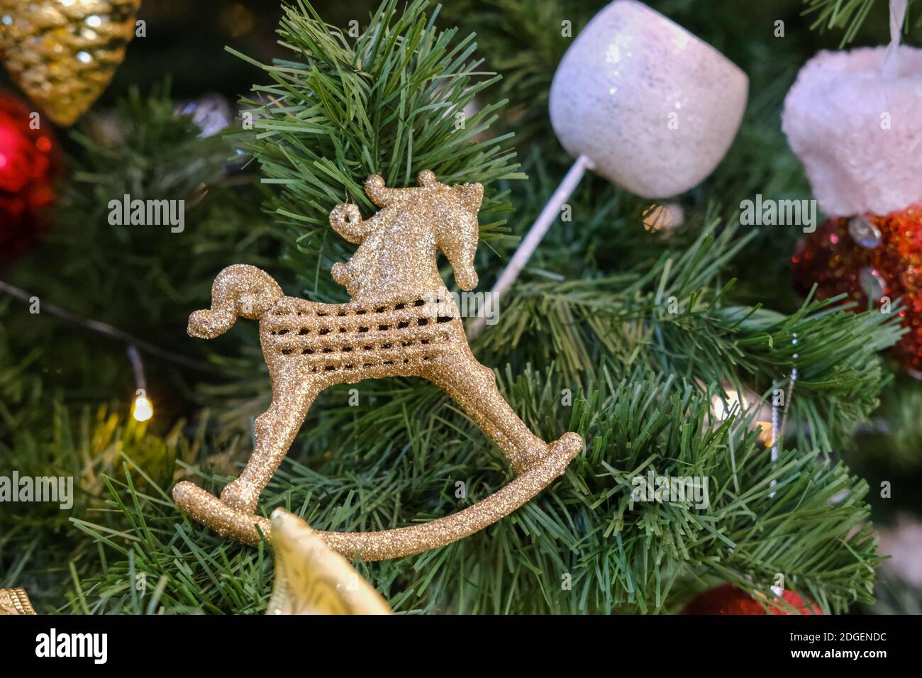 Jouet d'arbre de Noël sous forme de cheval doré accroché aux branches Banque D'Images