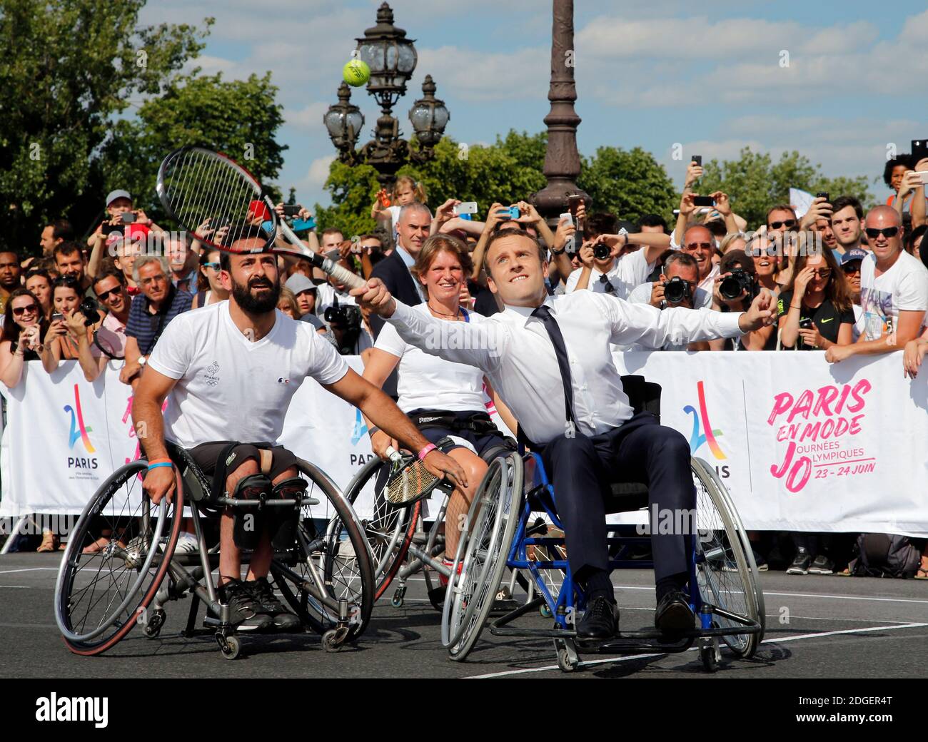 Le président français Emmanuel Macron retourne le ballon en fauteuil roulant  alors qu'il joue au tennis sur le pont Alexandre III à Paris, France, le 24  juin 2017. La capitale française est