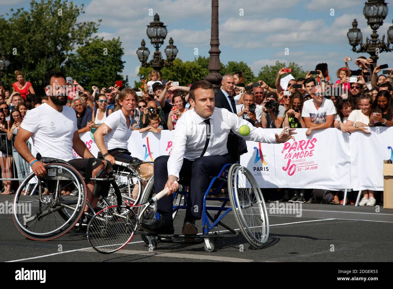 Le président français Emmanuel Macron retourne le ballon en fauteuil roulant  alors qu'il joue au tennis sur le pont Alexandre III à Paris, France, le 24  juin 2017. La capitale française est