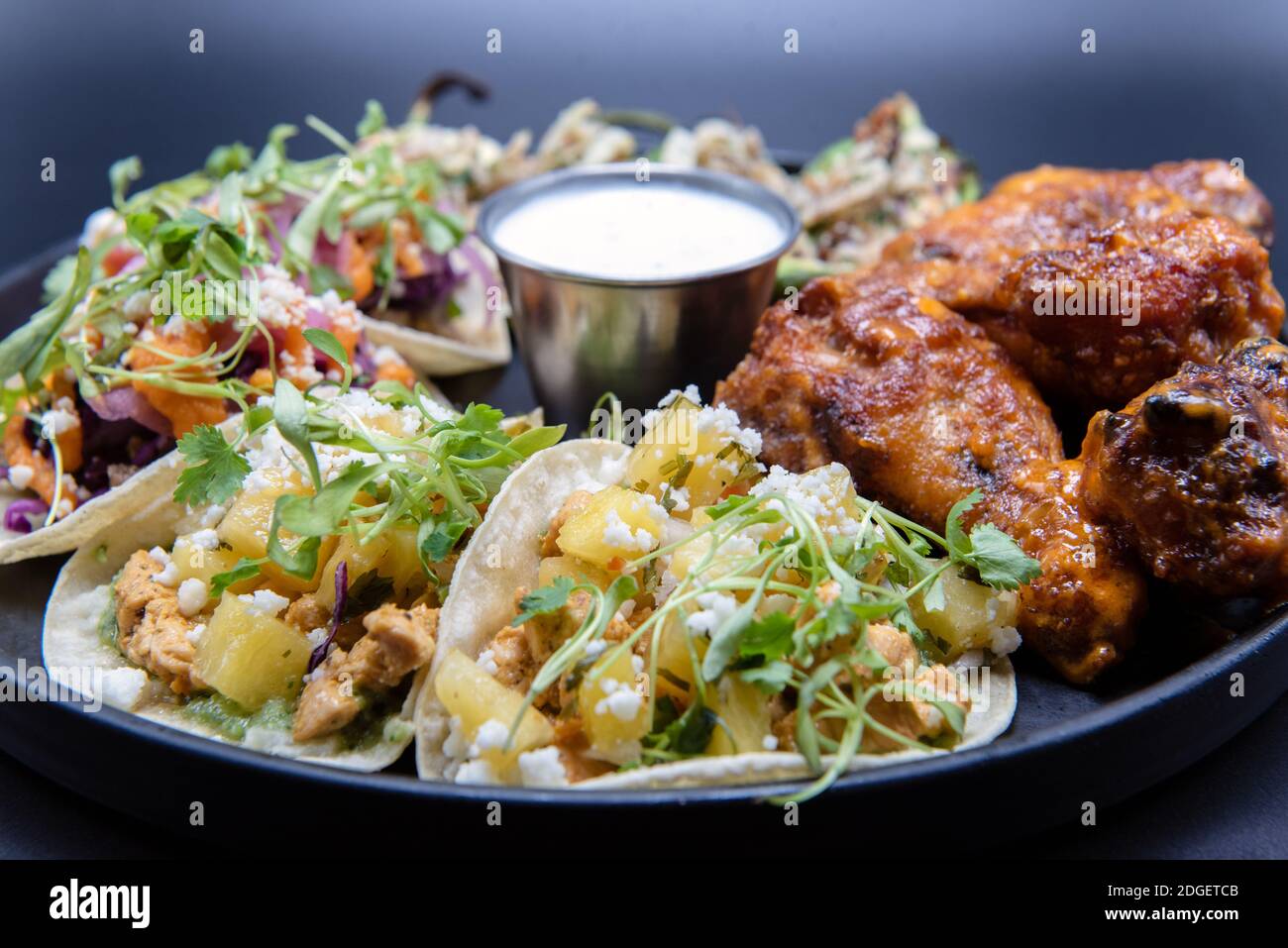 Une délicieuse assiette de dégustation de hors-d'œuvre avec des tacos au poulet et au steak, des boutons-pression et des ailes de buffle fait que l'eau de la bouche et l'estomac croissent. Banque D'Images