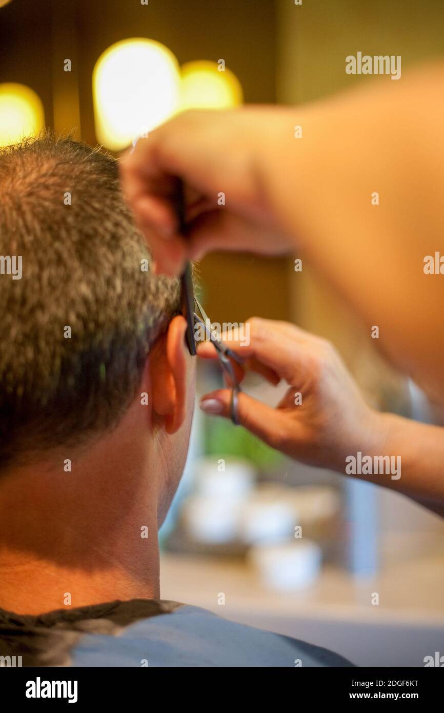 Coiffeur rasage tête d'homme avec tondeuse à cheveux ou tondeuse à cheveux, vue de derrière le client. Banque D'Images