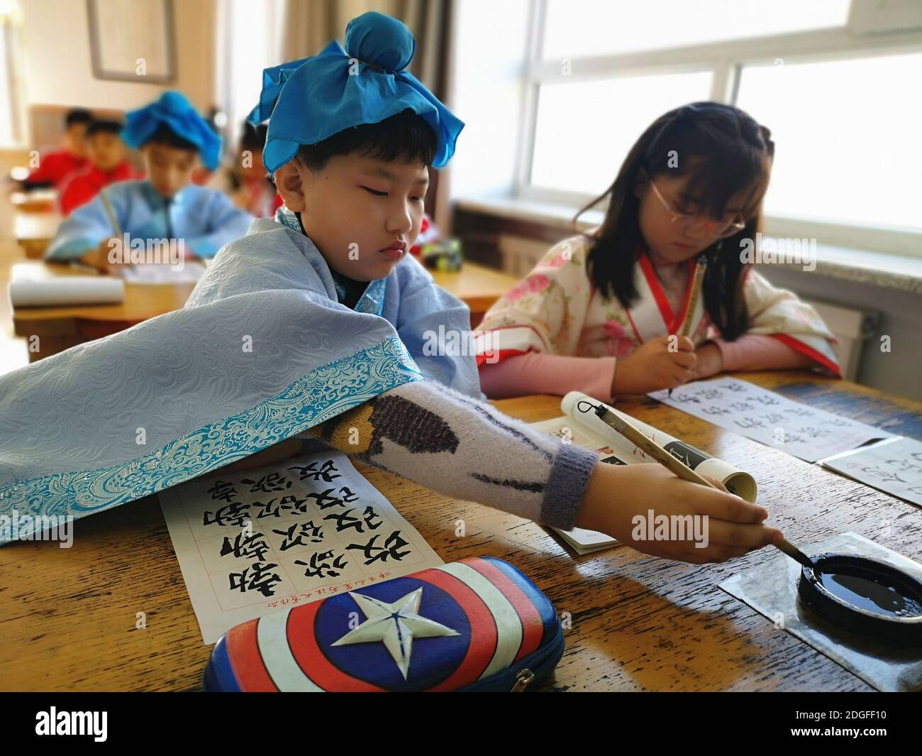 Les élèves de l'école primaire vêtus de Hanfu, un costume traditionnel chinois, écrivent la calligraphie et apprennent la culture traditionnelle dans la ville de Jilin, au nord-est Banque D'Images