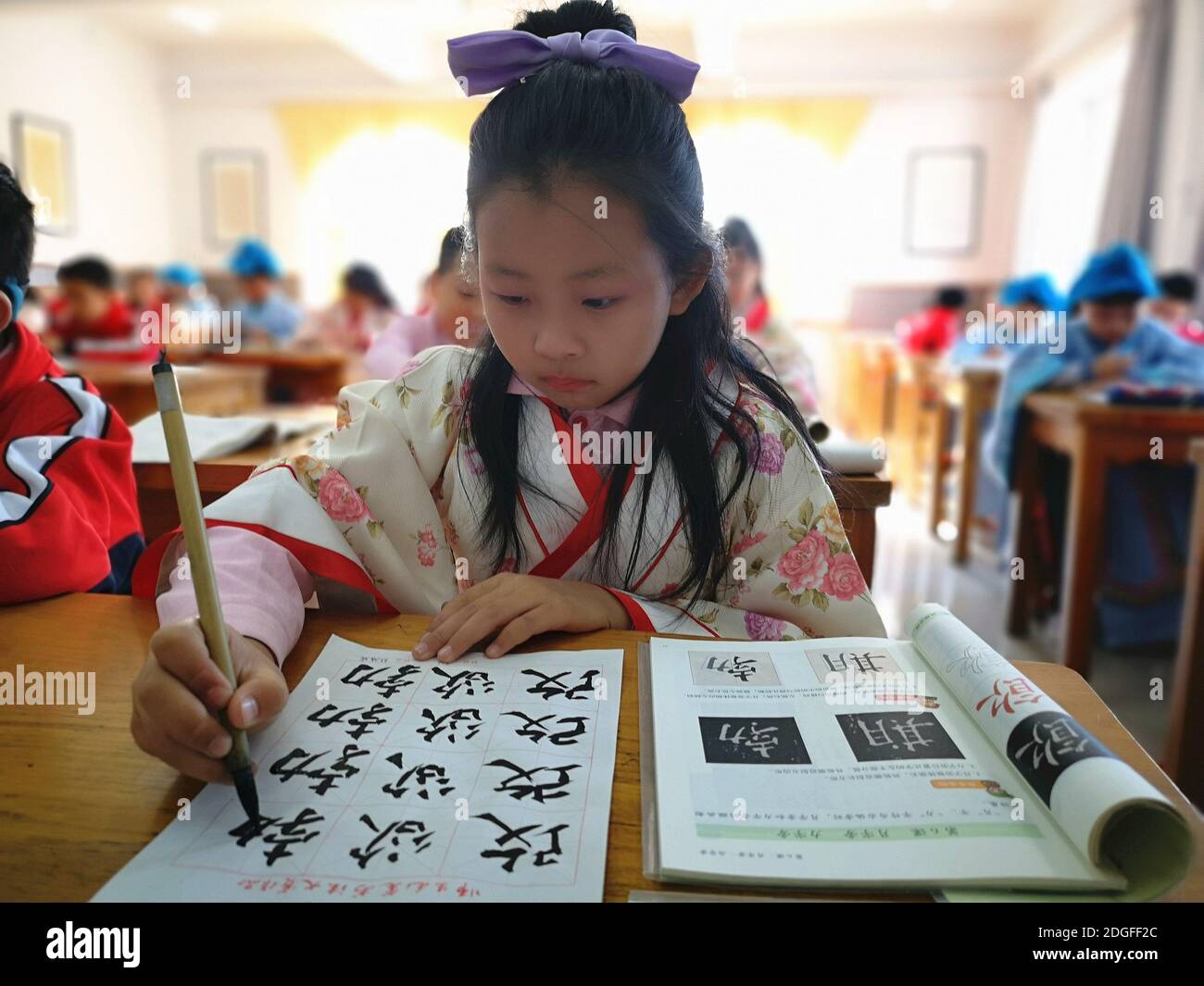 Les élèves de l'école primaire vêtus de Hanfu, un costume traditionnel chinois, écrivent la calligraphie et apprennent la culture traditionnelle dans la ville de Jilin, au nord-est Banque D'Images